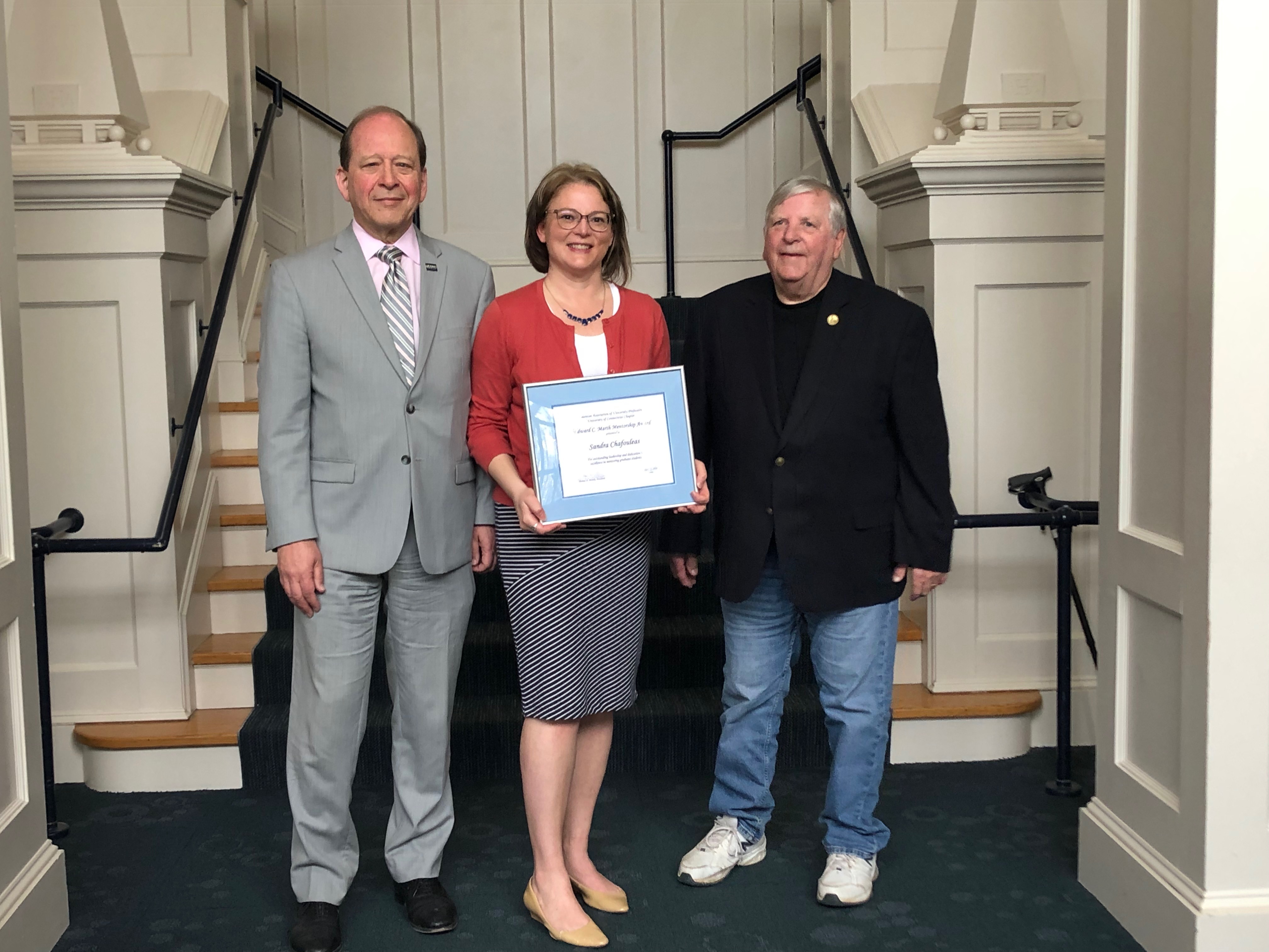 Kent Holsinger, Sandra Chafouleas holding award, Edward C. Marth in front of steps