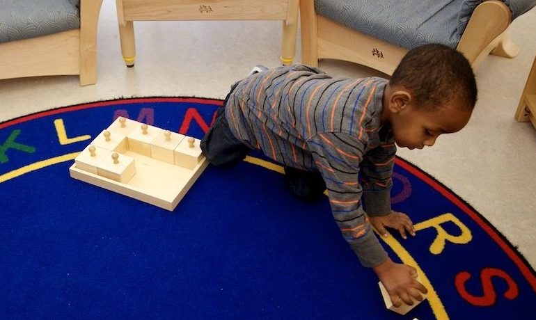 African American preschool aged boy playing with blocks on blue rug