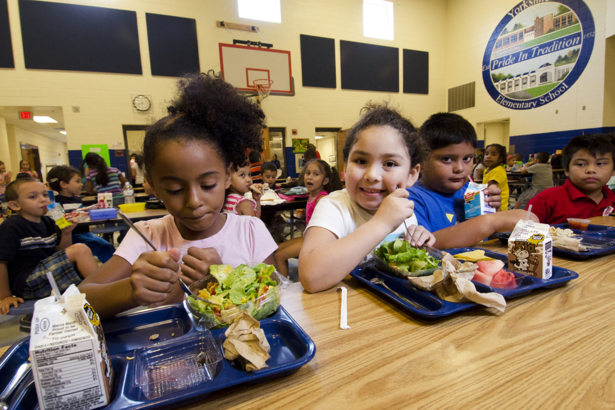 Racially/ethnically diverse children eating at table in cafeteria