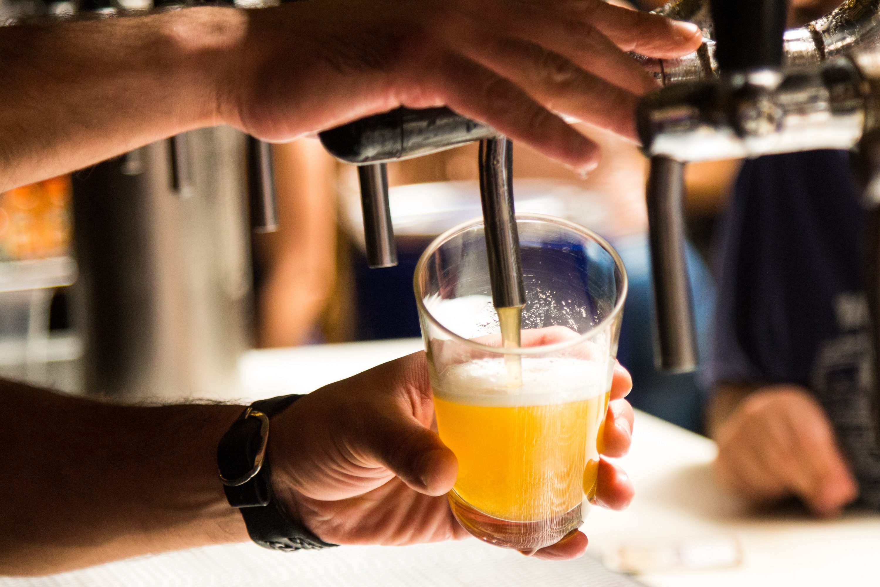 man pouring beer out of a tap into a glass