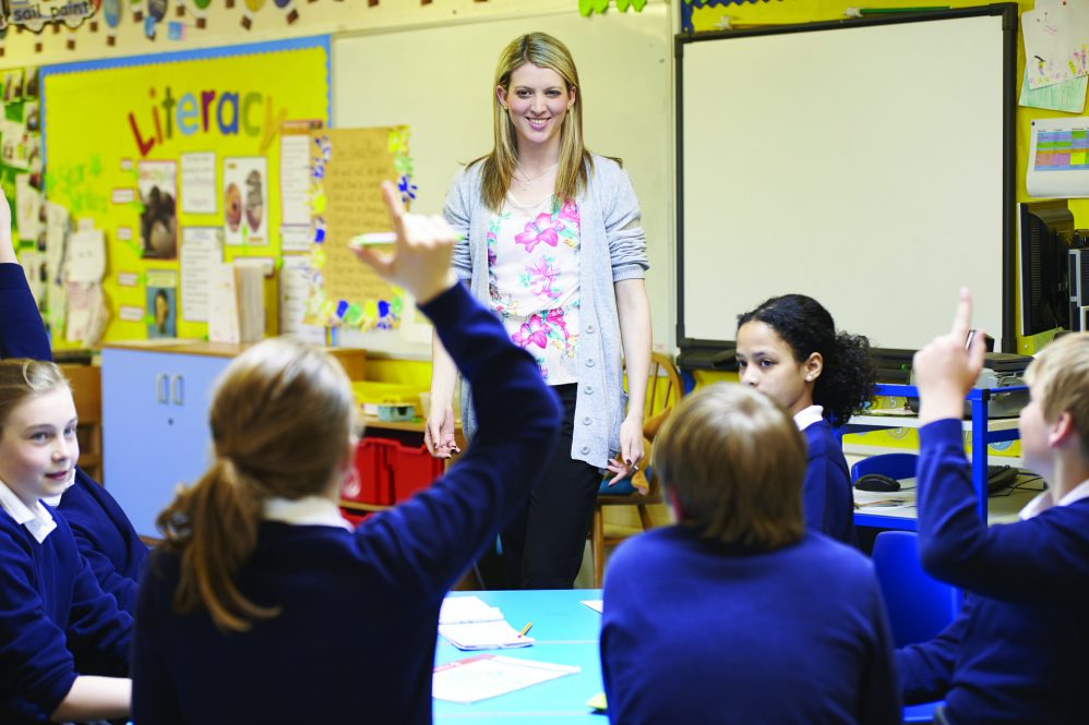 white blinde teacher in classroom with girls in blue sweater school uniforms