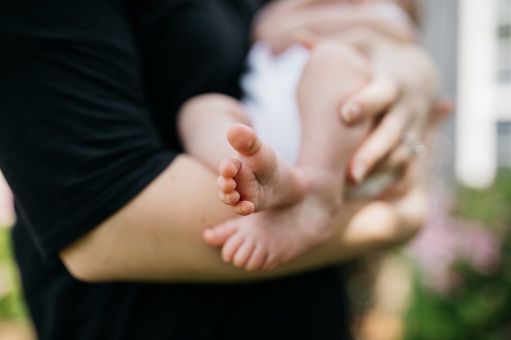 woman holding a baby in diaper; Baby's feet are towards camera.