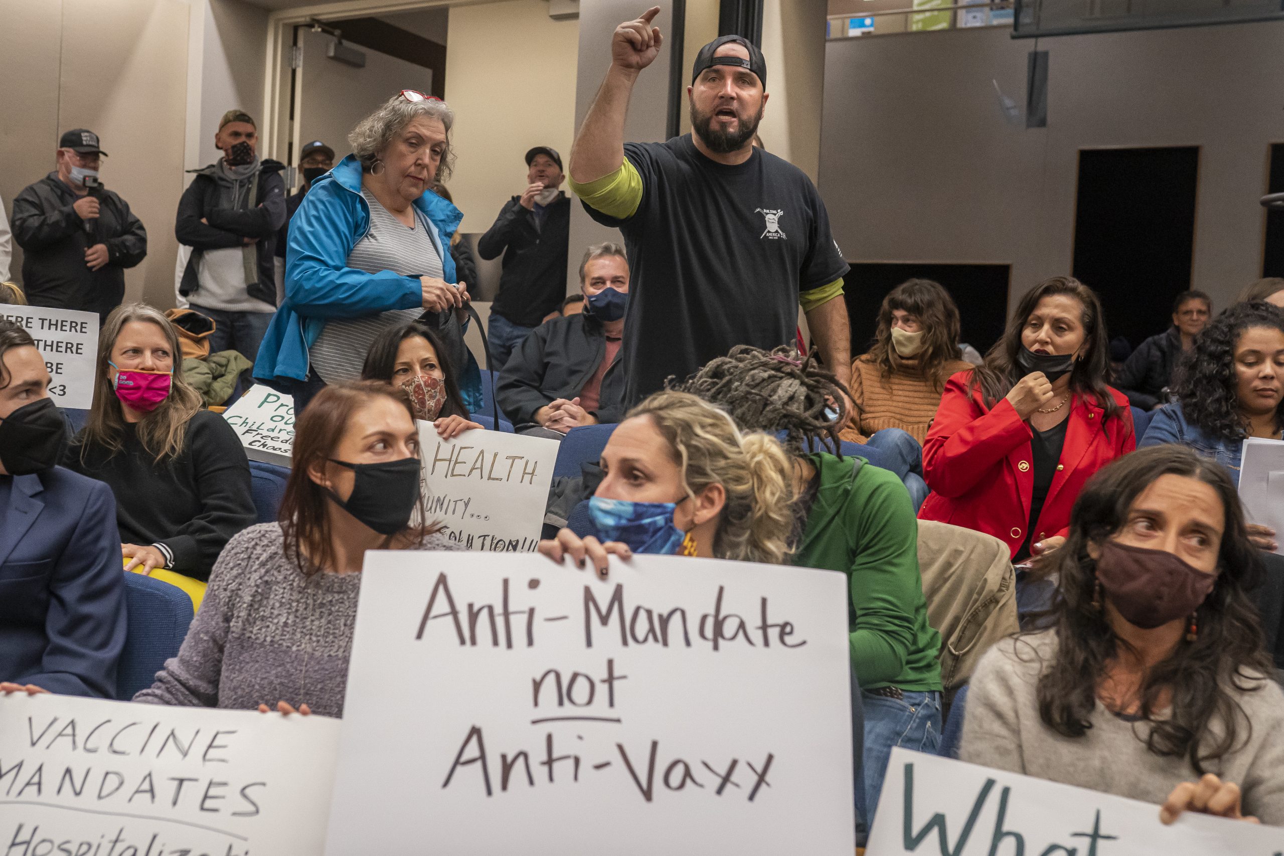 group of people in school board meeting holding anti-mandate signs Nathan Howard/Getty Images