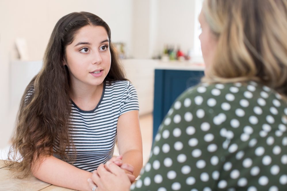 adult and teen girl talking at table