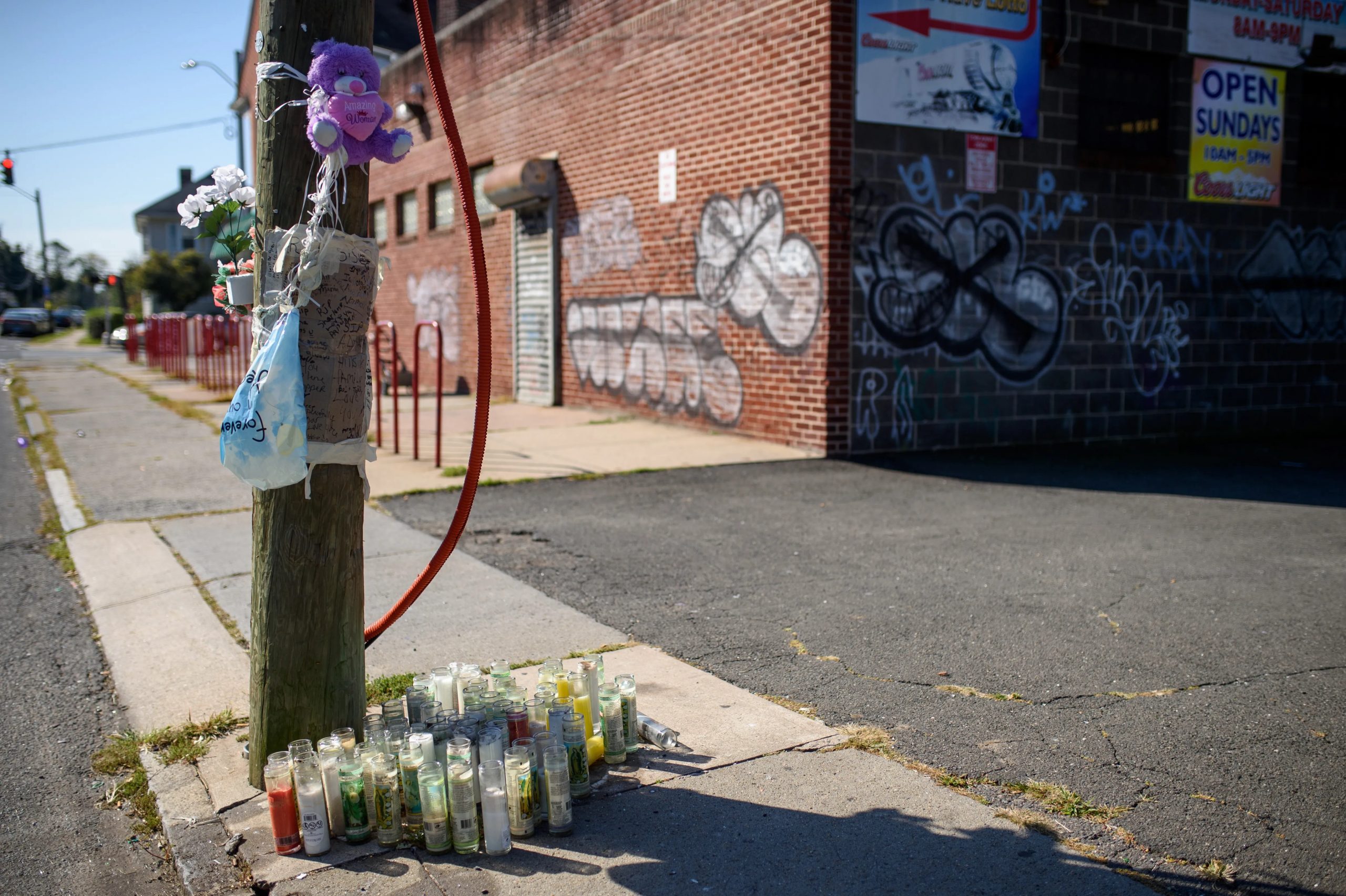 candles and a teddy bear surround a utility pole