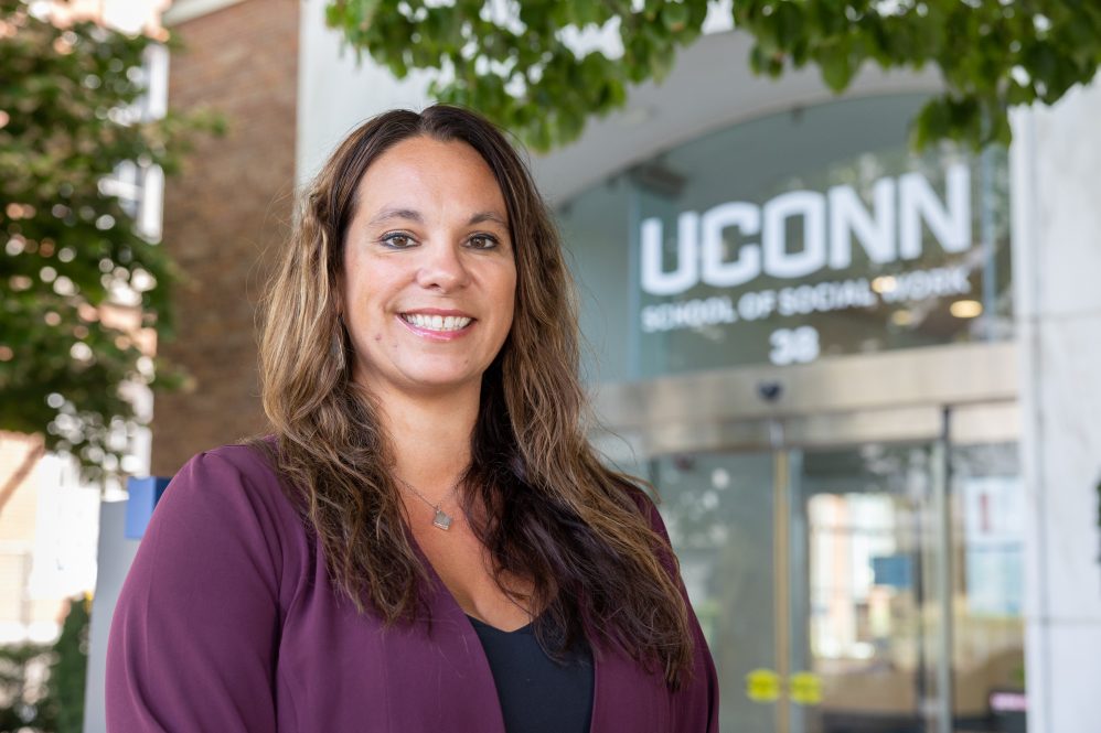 Christina Mogro-Wilson stands in front of the School of Social Work