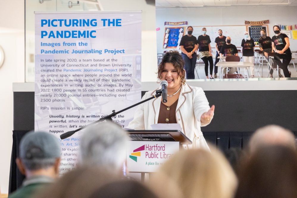 Teen girl speaks at podium with microphone in front of blurred audience
