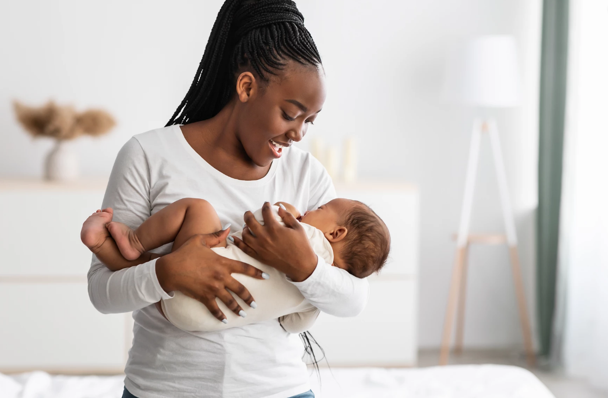 Black mother holding infant in her arms and smiling
